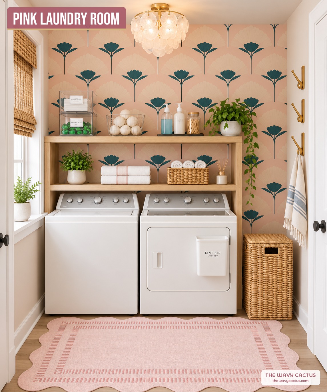 Pink laundry room with pink and dark teal fan flower wallpaper, a white washer and dryer, a capiz shell flush ceiling light, gold wall hooks, wire baskets, a woven hamper, and a pink scalloped rug